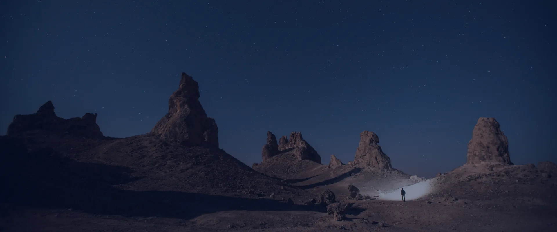 An explorer's light cutting through a starlit landscape